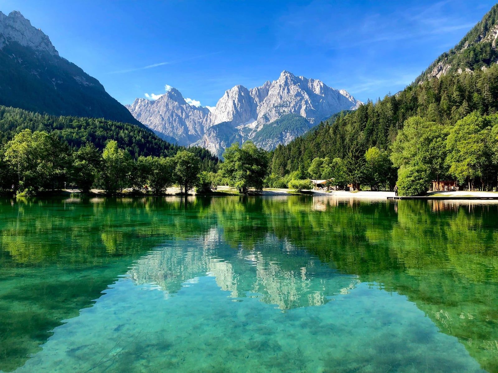 Das klare türkisfarbene Wasser des Jasna-Sees spiegelt die bewaldeten Ufer und die gewaltigen Gipfel der Julischen Alpen bei Kranjska Gora.