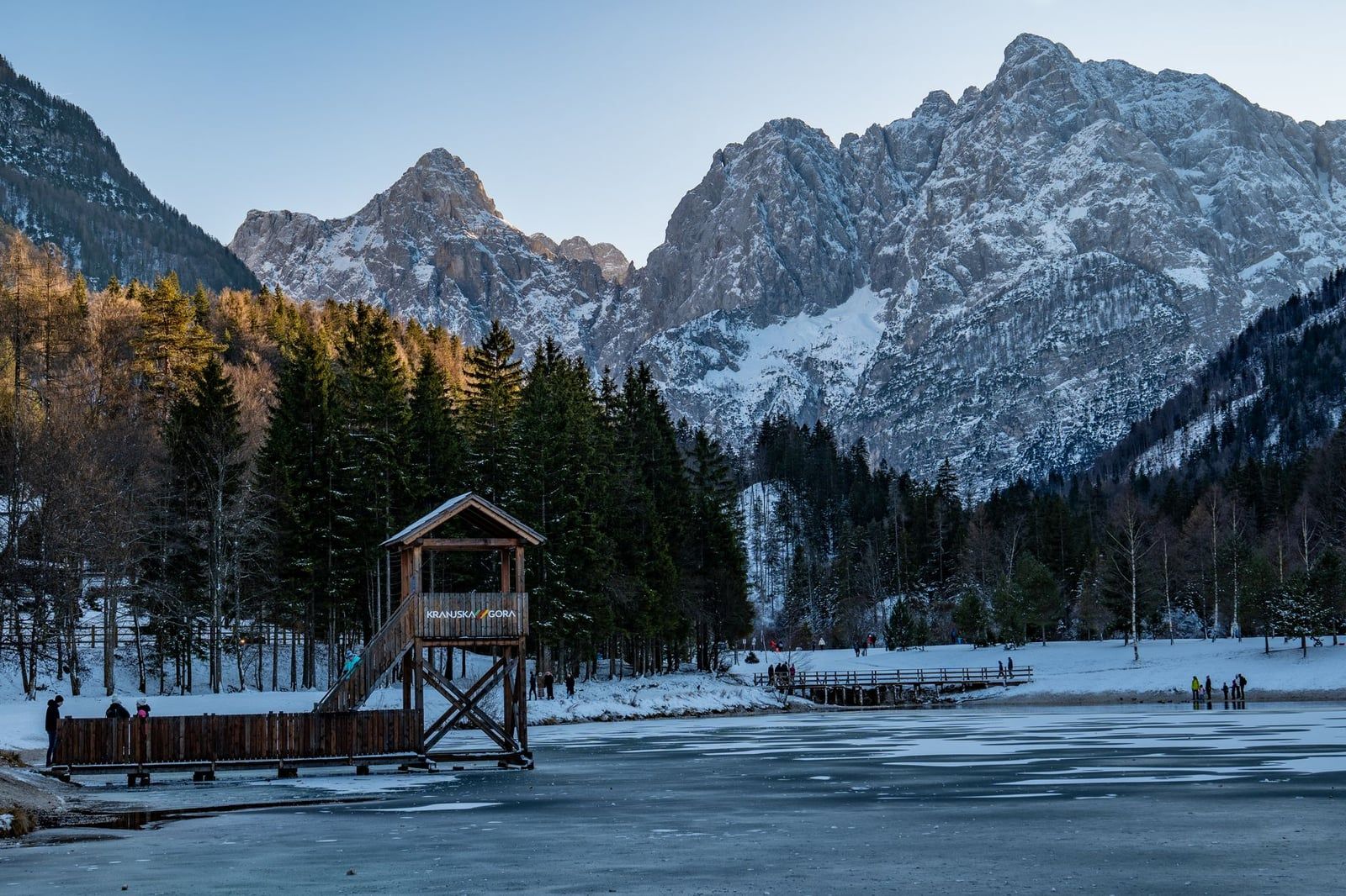 Een houten steiger op het bevroren oppervlak van Lake Jasna tegen de besneeuwde Julische Alpen bij Kranjska Gora in het Triglav Nationaal Park.